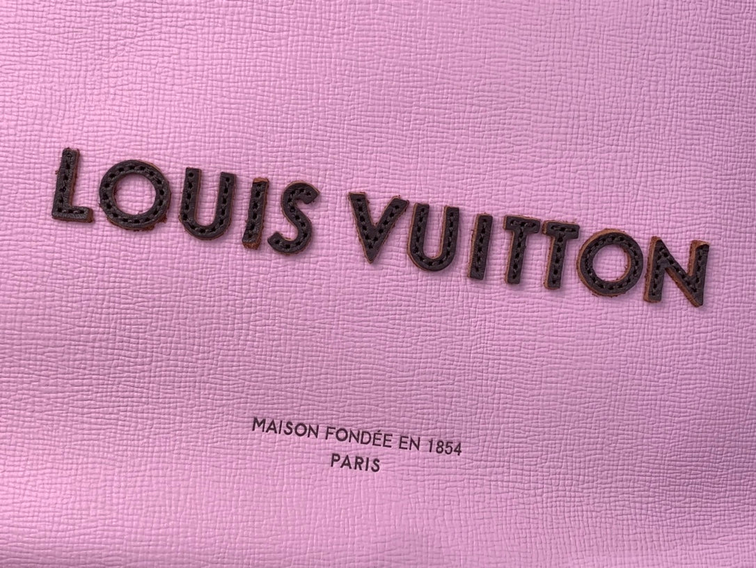 Louis Vuitton logo on textured pink leather bag, with “Maison fondée” text