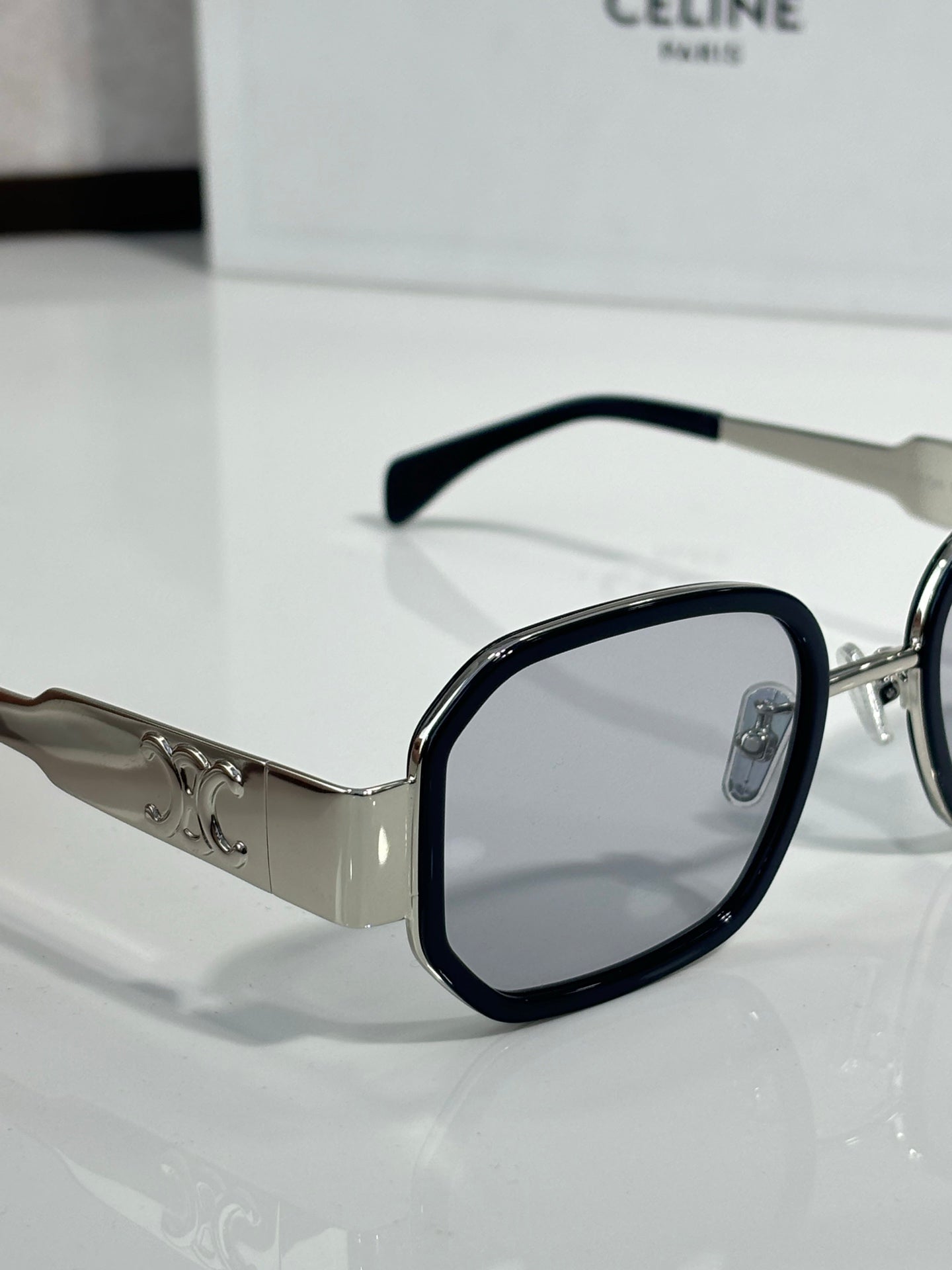 Clear-lens sunglasses with black-tinted frames and silver logo temples
