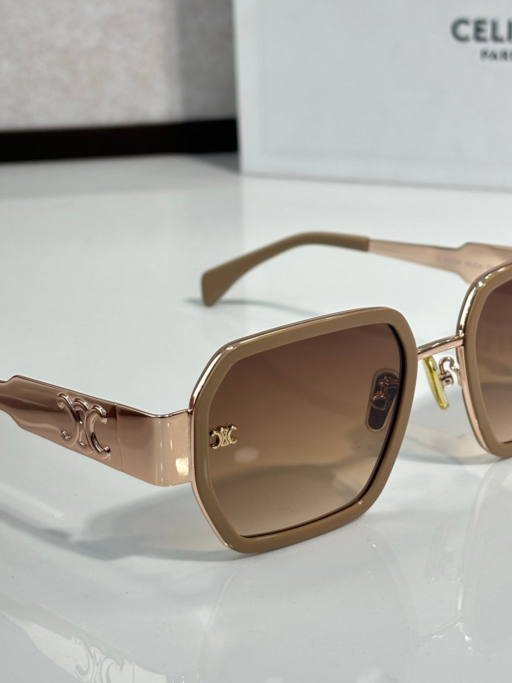 Square brown sunglasses with tinted lenses and gold logo engraved on the temple