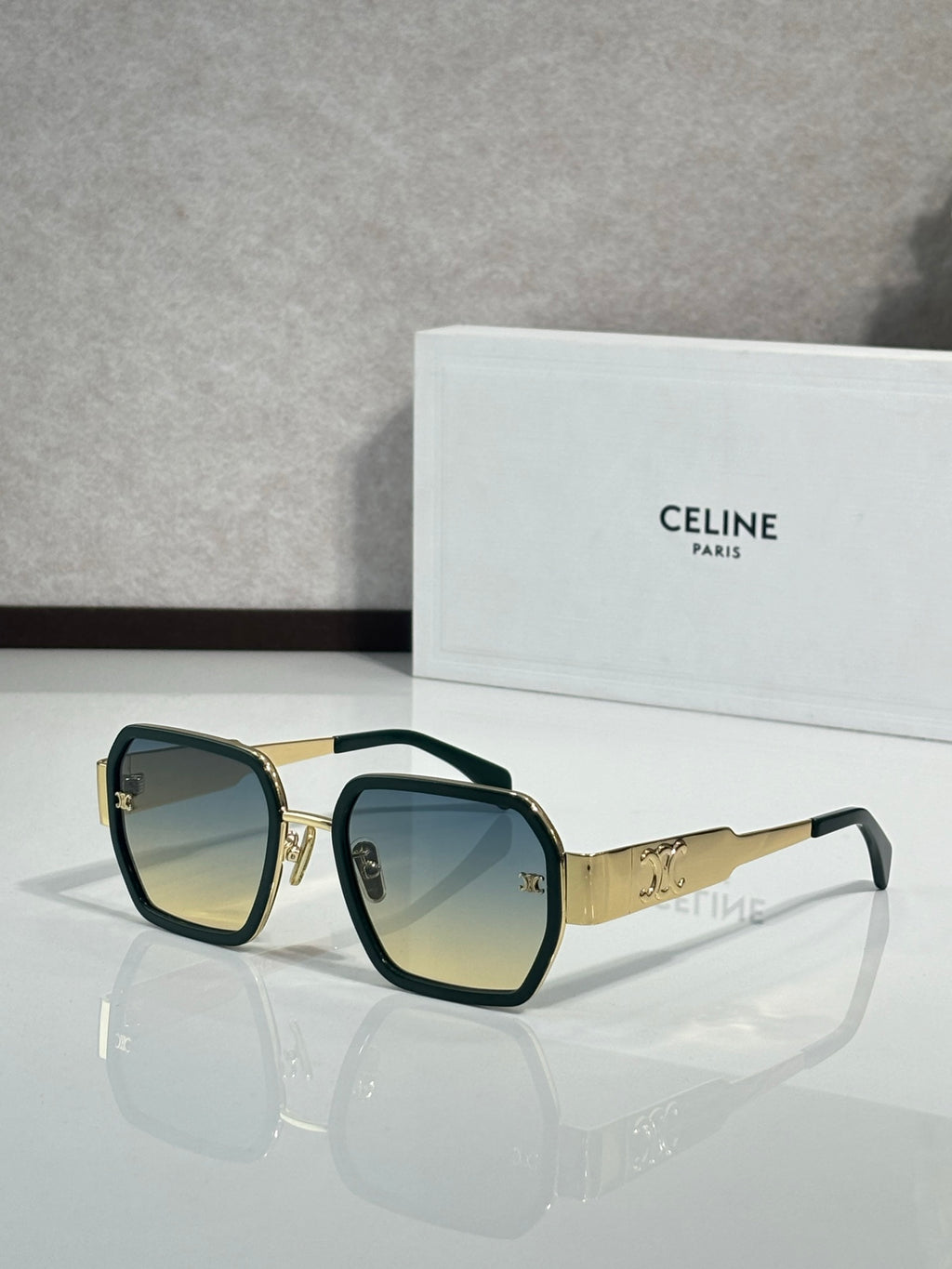 Square dark sunglasses with gold frame details and dark lenses on the temples