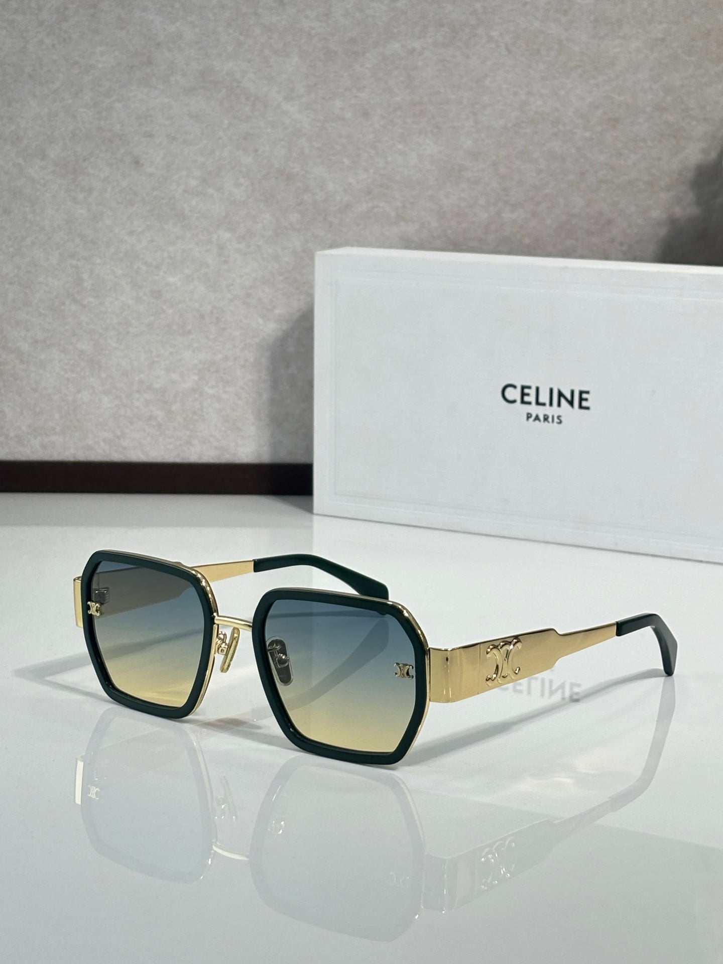 Square dark sunglasses with gold frame details and dark lenses on the temples