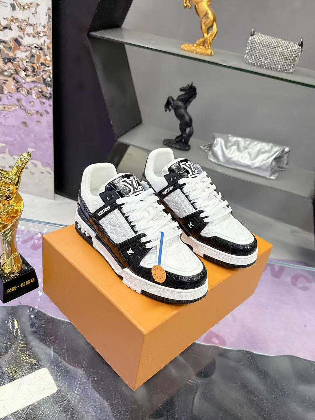 Louis Vuitton ladies sneakers on orange box, black leather with white laces and trim.