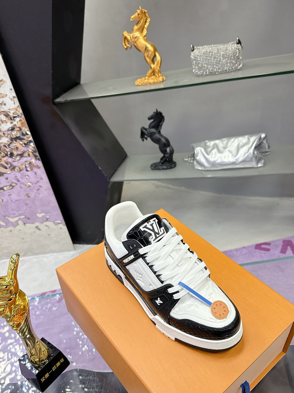 Louis Vuitton ladies sneakers on orange box, white panels with black side stripes and laces.
