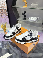 Louis Vuitton ladies sneakers on orange box, angled pair with white laces and black trim.