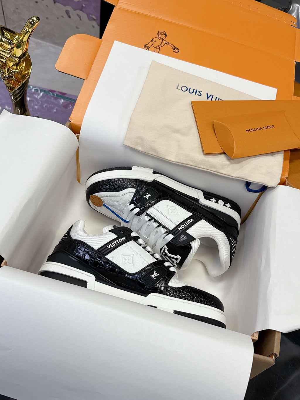 Louis Vuitton ladies sneakers, black and white, in presentation box with laces visible.