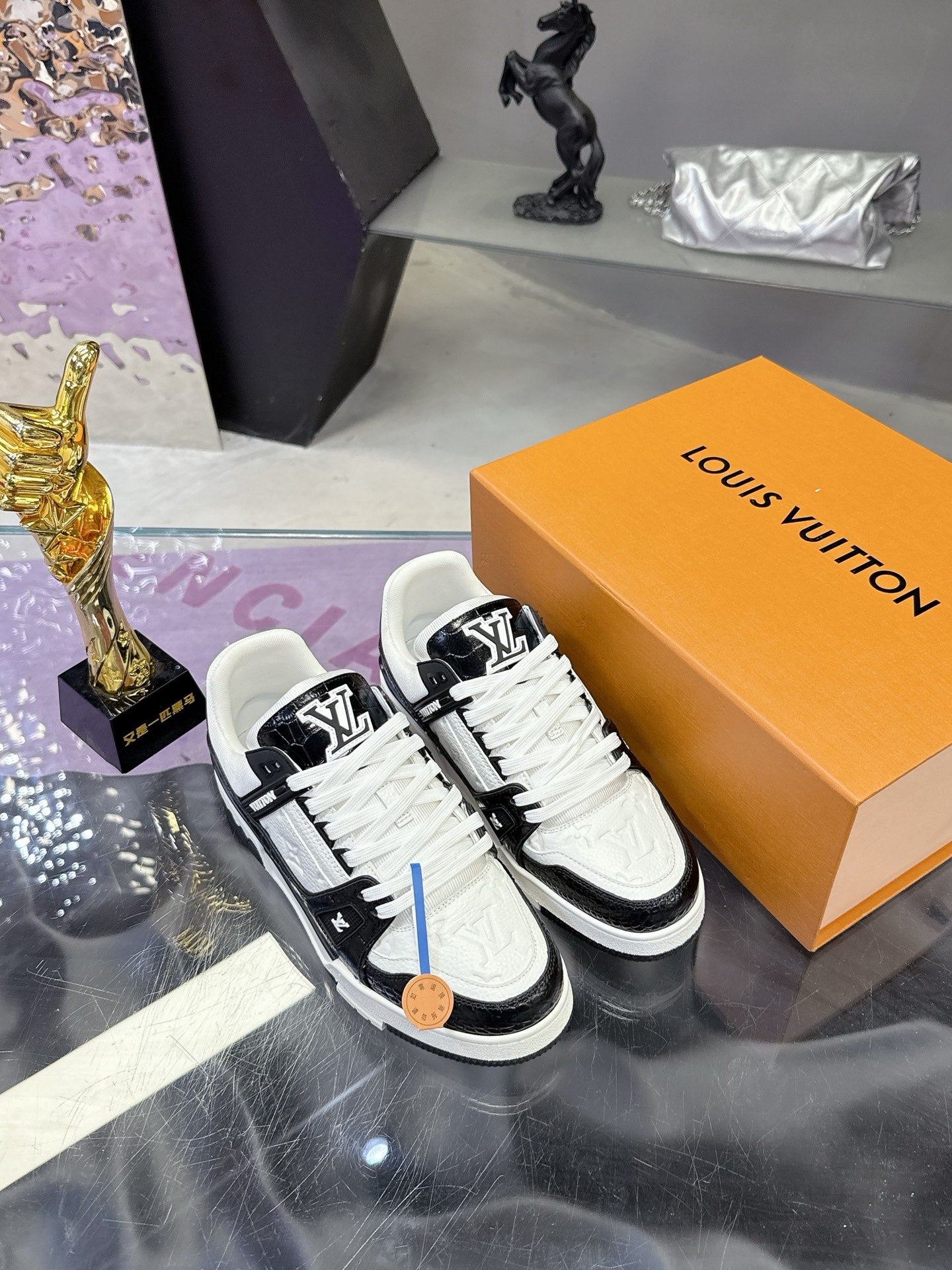 Louis Vuitton ladies sneakers on orange box, front view with black-and-white upper details.