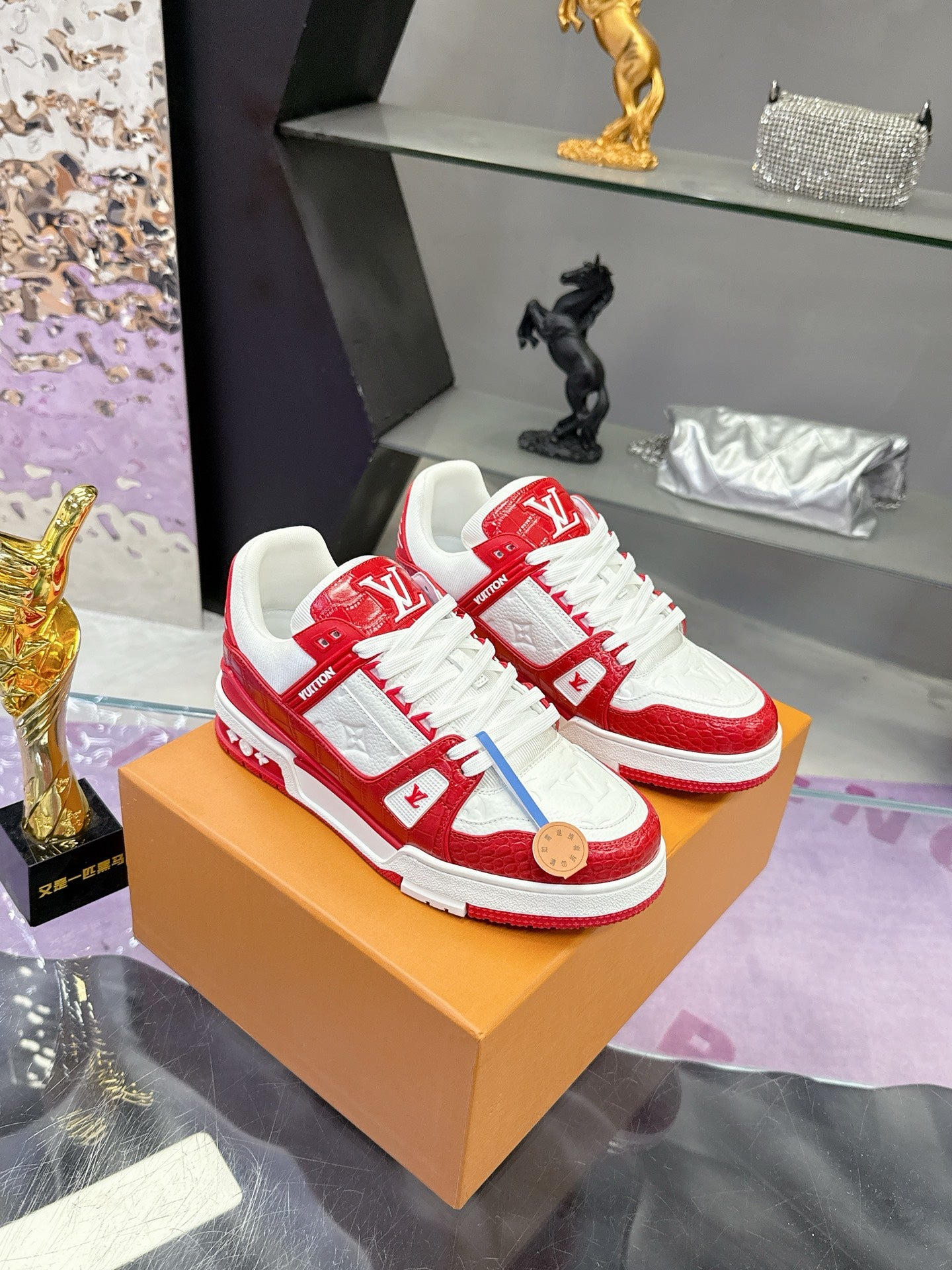 Louis Vuitton red-and-white low-top sneakers on a tan box with white rubber sole