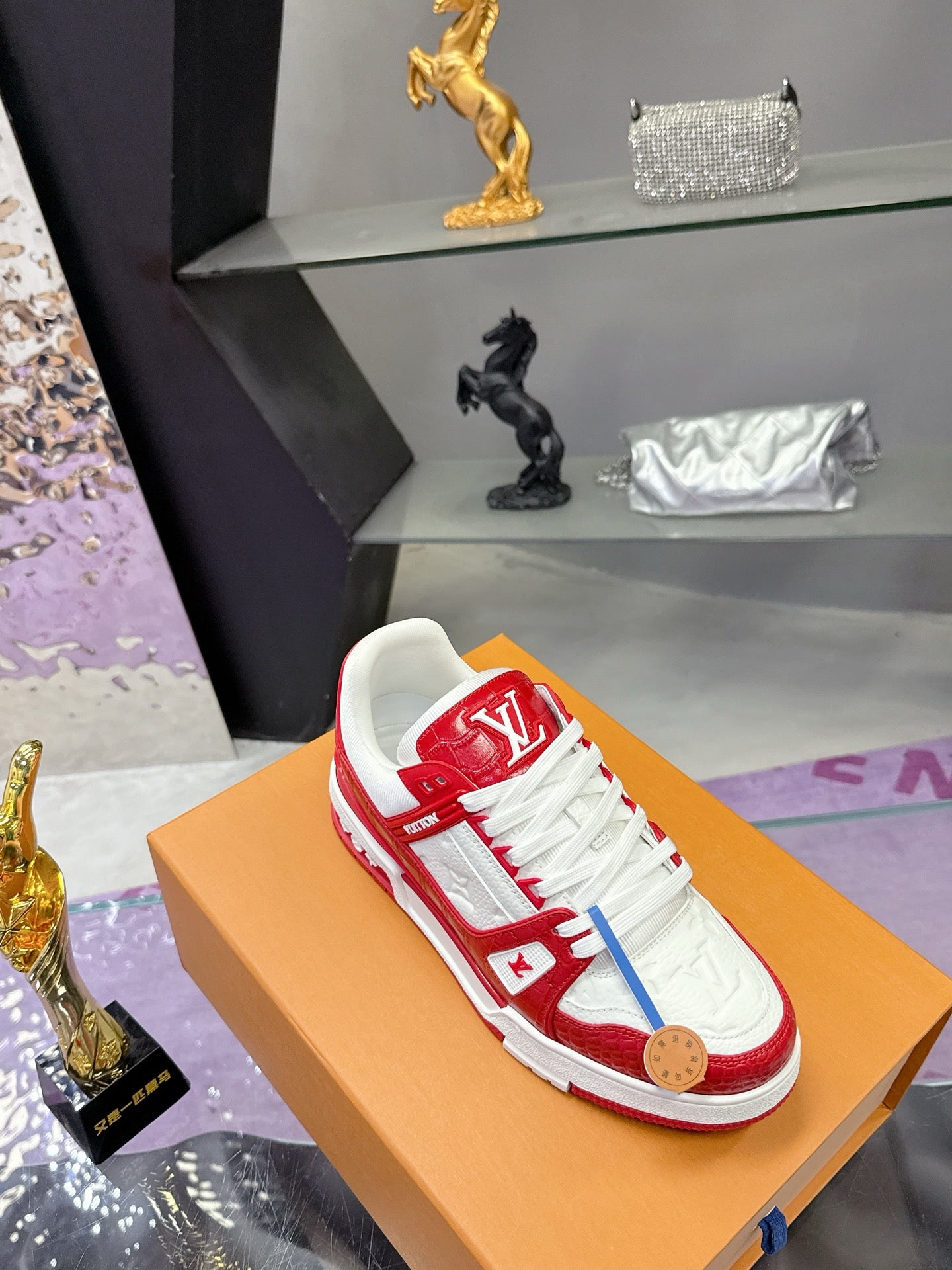 Louis Vuitton red-and-white low-top sneakers with white laces on a tan shoebox