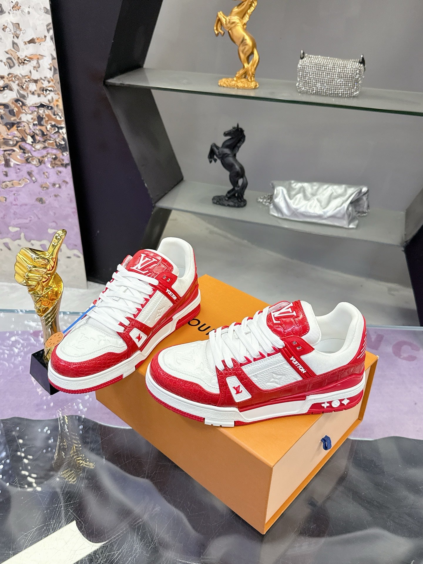 Louis Vuitton red-and-white low-top sneakers paired on a tan display box