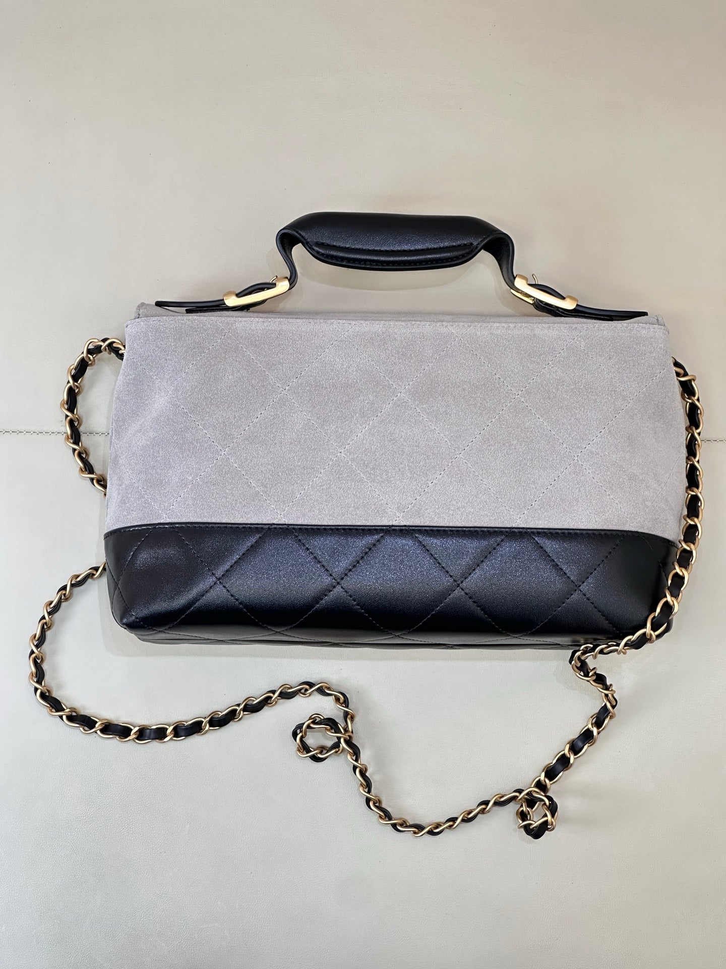 Chanel handbag with light gray top flap and dark navy quilted front, gold chain strap