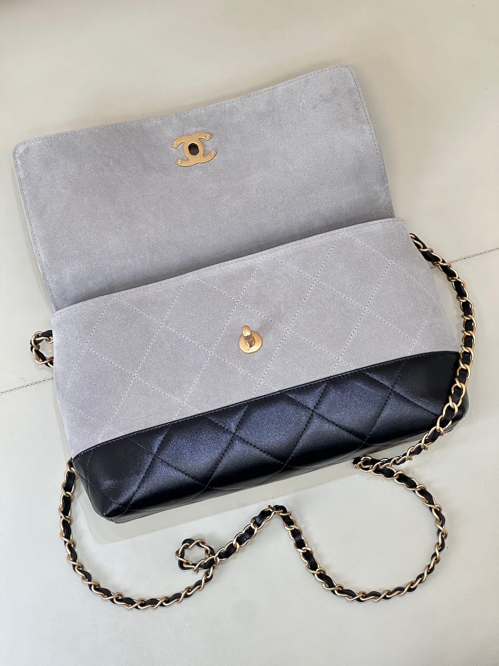 Chanel flap bag in light gray with dark navy quilted lower band, gold-tone chain strap