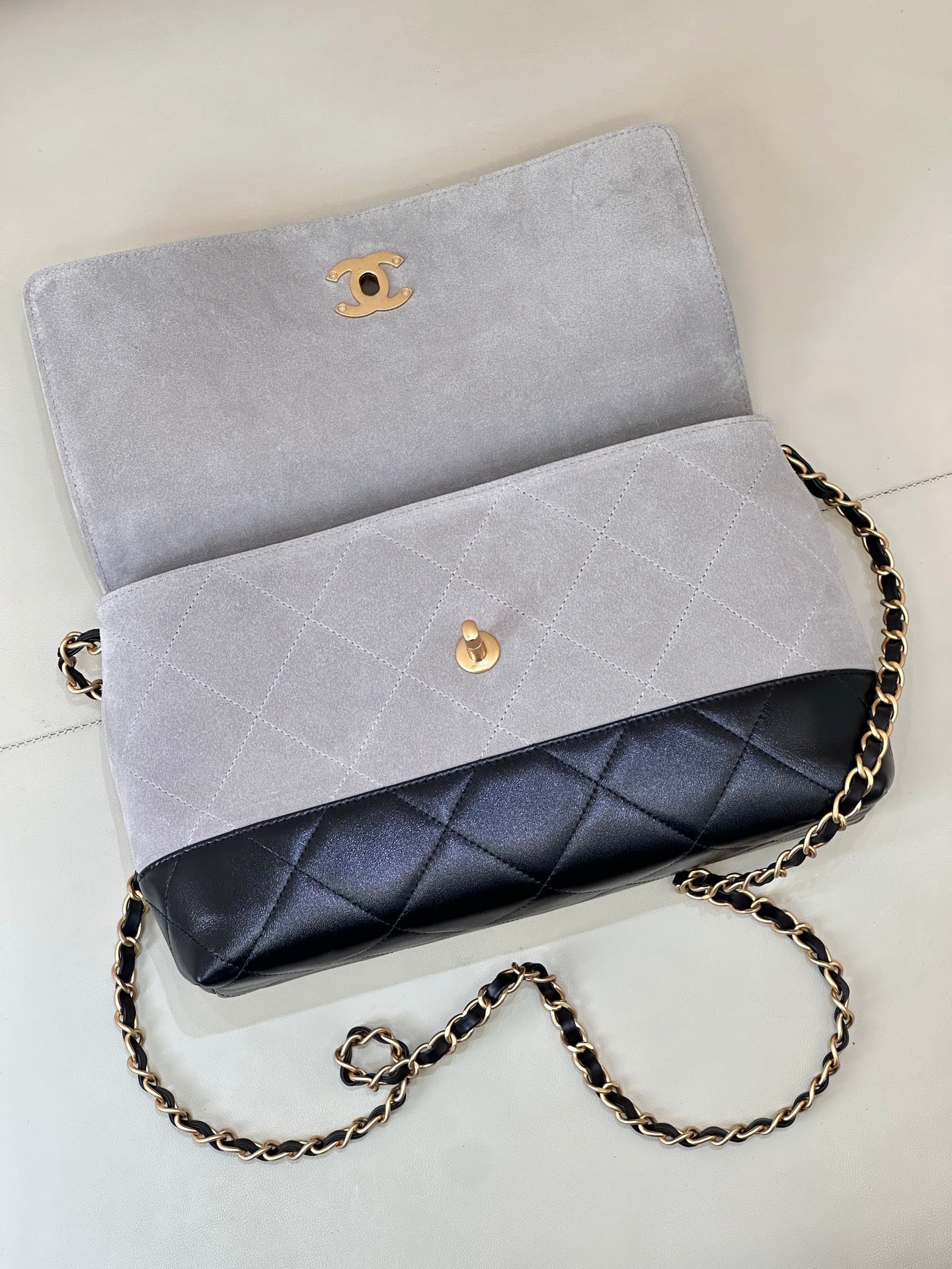 Chanel flap bag in light gray with dark navy quilted lower band, gold-tone chain strap