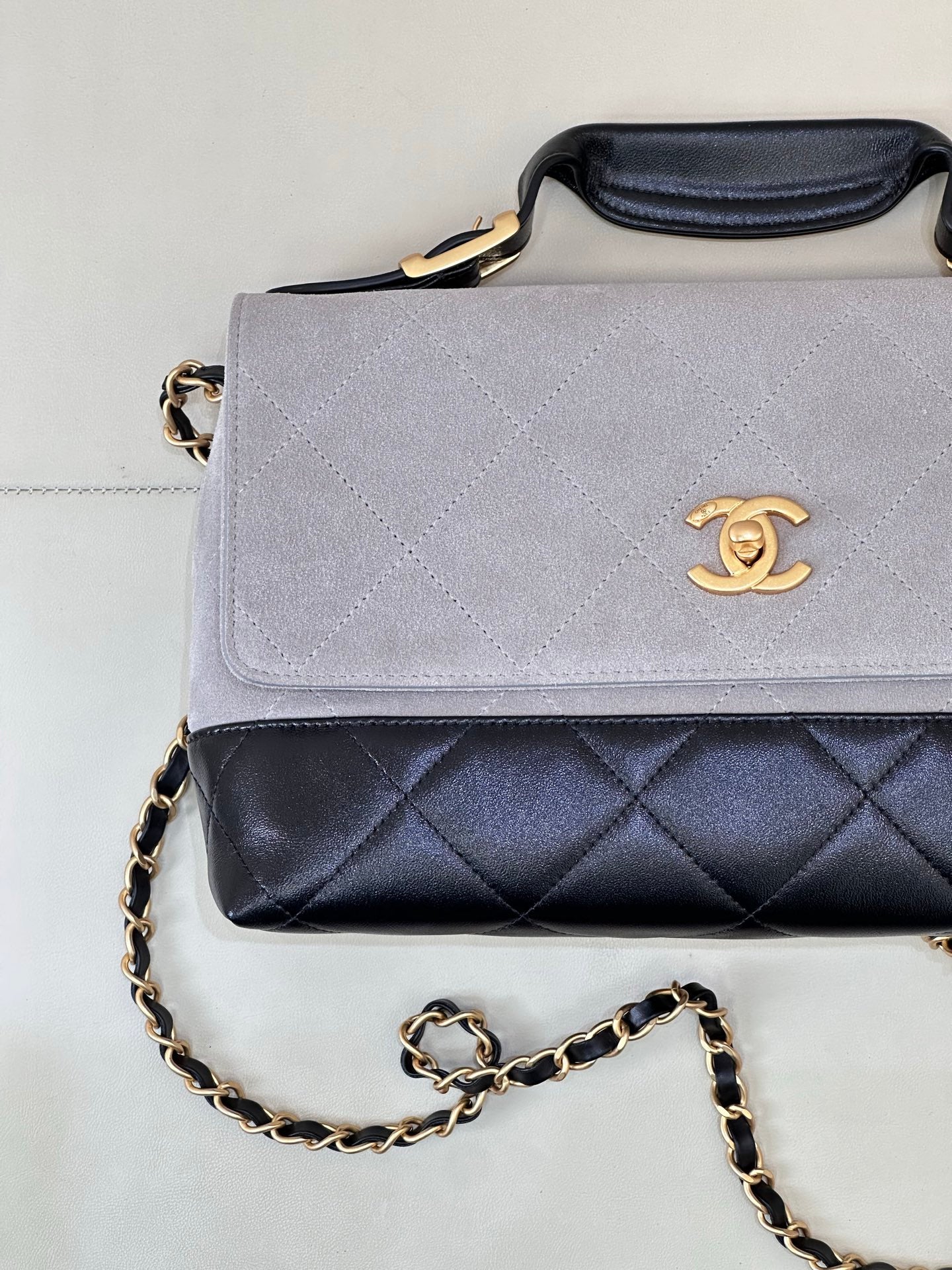 Chanel flap handbag with light gray front and dark navy quilted base, gold chain strap