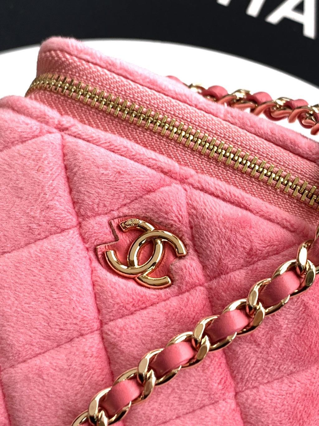 Pink quilted bag close-up with gold-tone zipper, CC charm, and chain strap