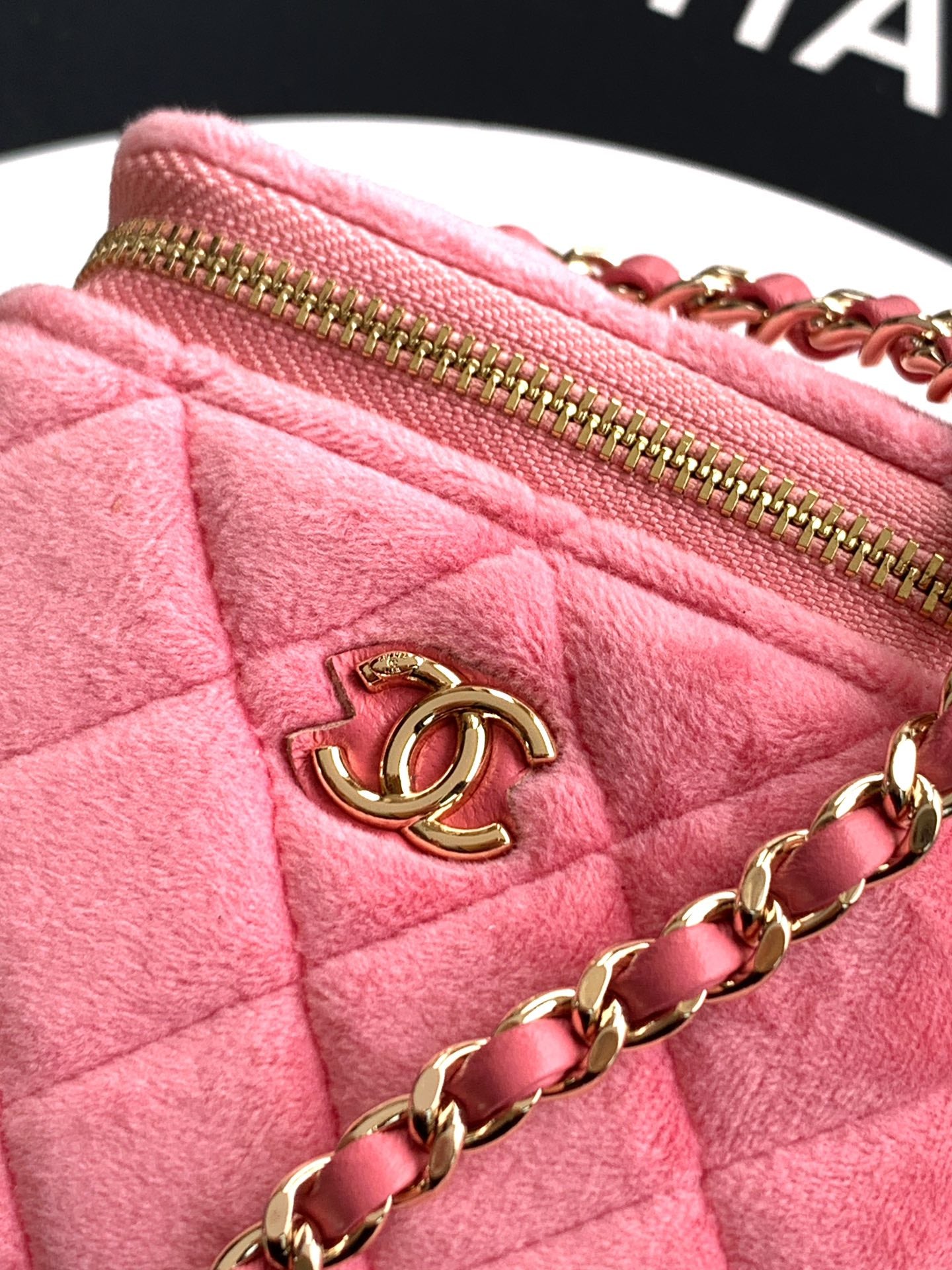 Pink quilted bag close-up with gold-tone zipper, CC charm, and chain strap