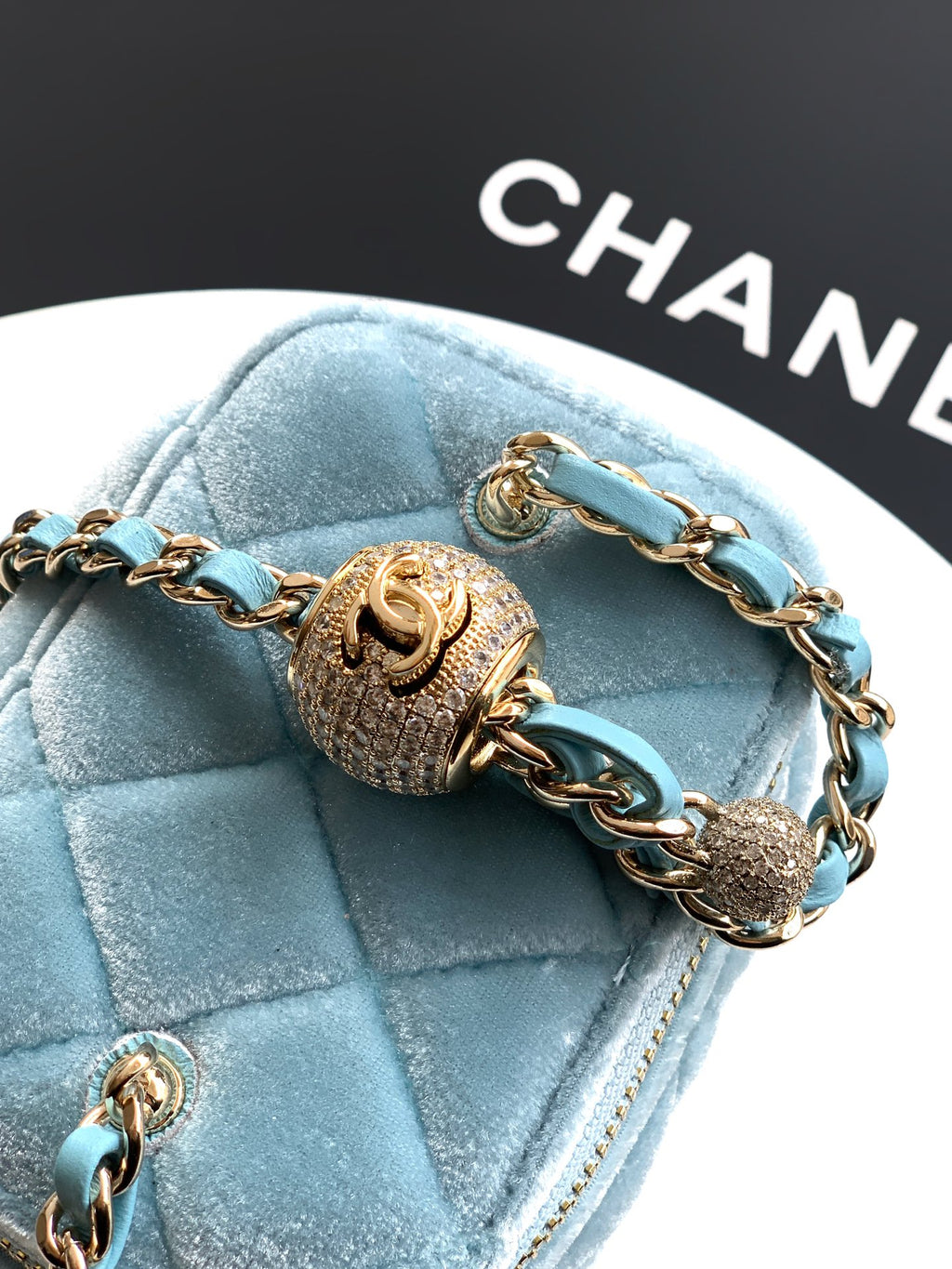 Chanel light blue quilted bag close-up with ornate gold charm and chain strap