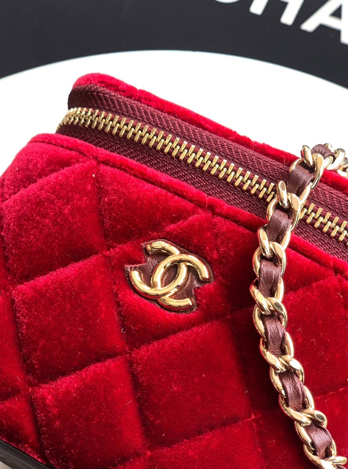 Red velvet Chanel mini bag close-up of gold zipper and chain with CC charm