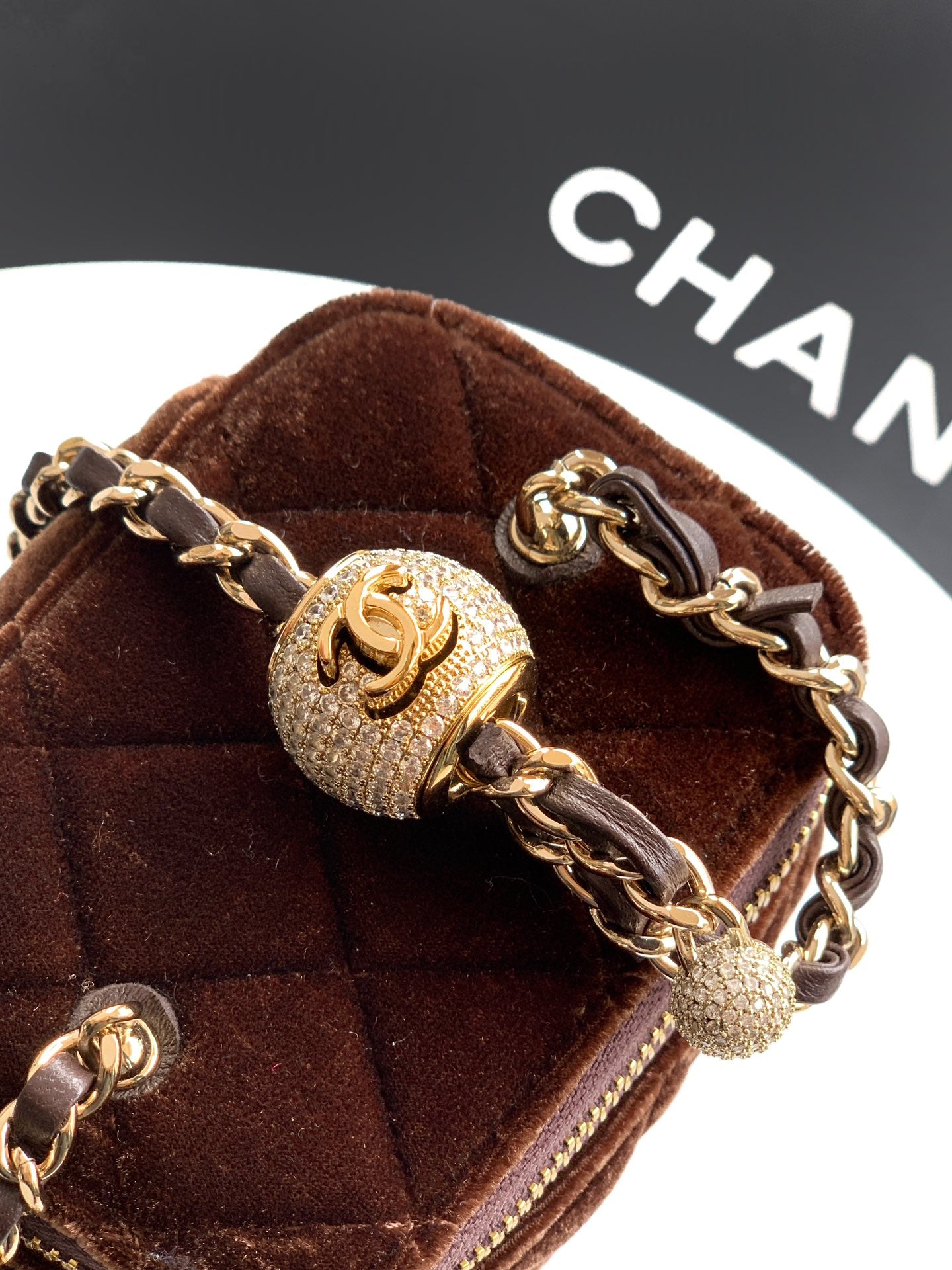 Brown quilted mini bag with gold-tone chain, textured CC charm and zip top