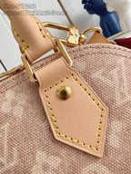 Mini monogram bag close-up: tan leather trim with gold snap and stitched edges