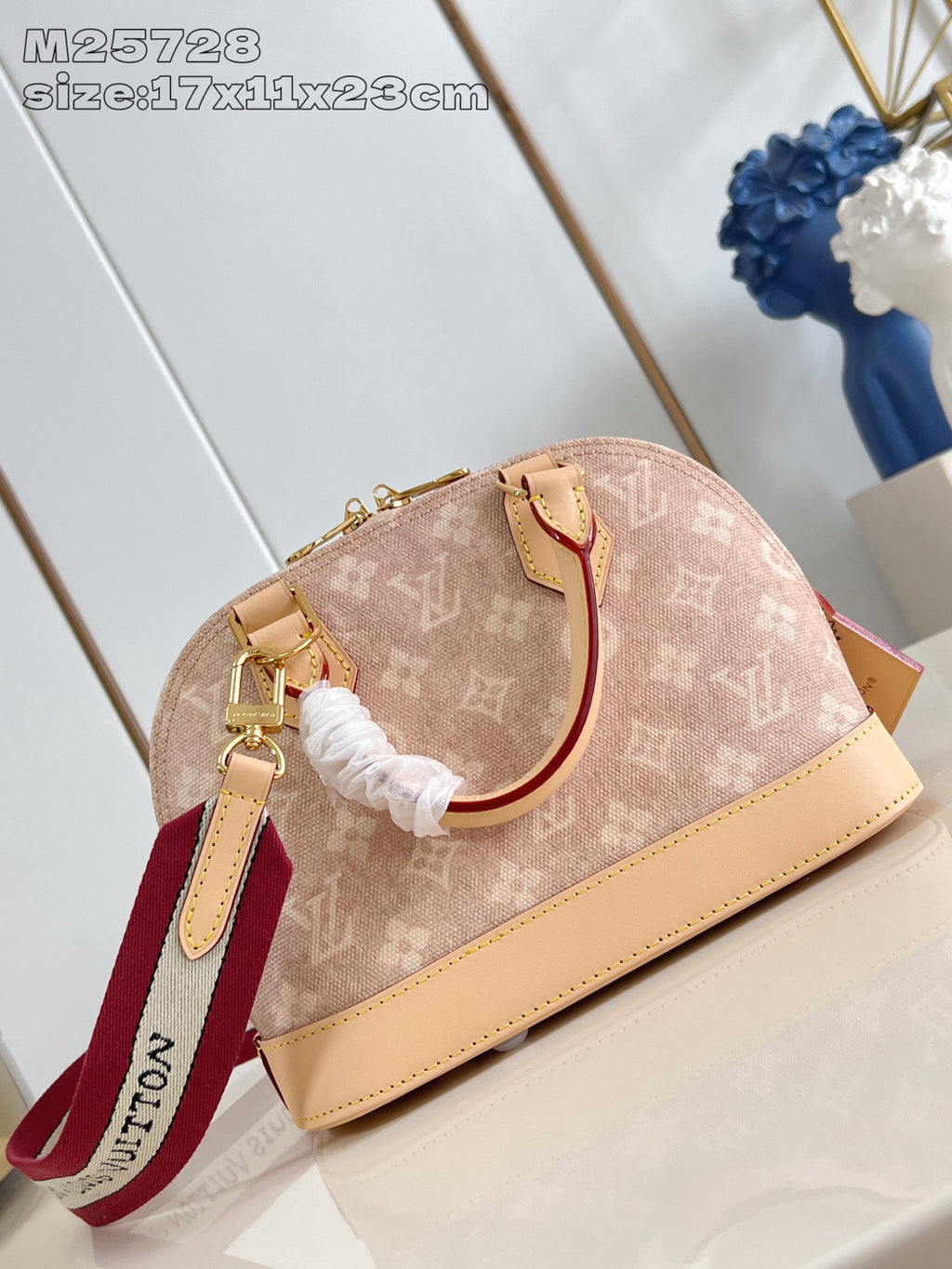 Mini monogram bag with tan leather base, white elastic tie, and red strap