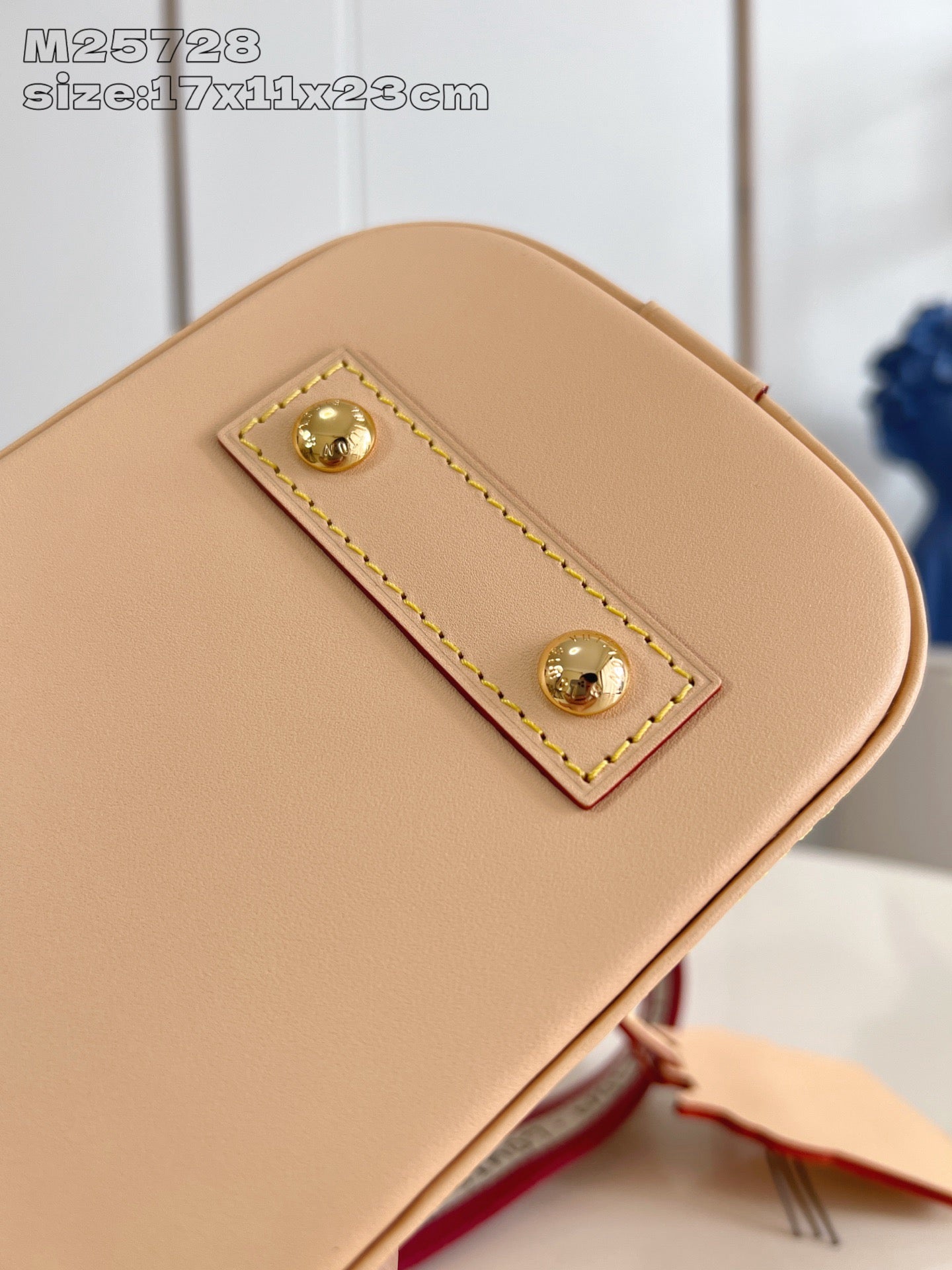 Mini tan bag exterior with rectangular gold-stud patch detail and stitched border