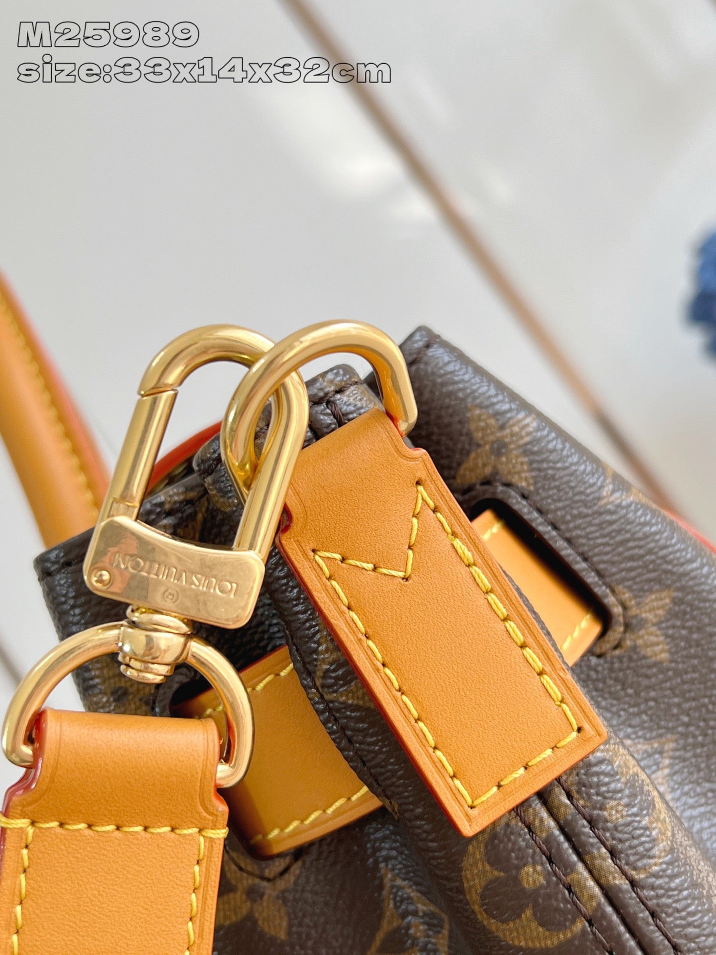 Louis Vuitton monogram handbag close-up of gold-tone padlock charm and tan strap
