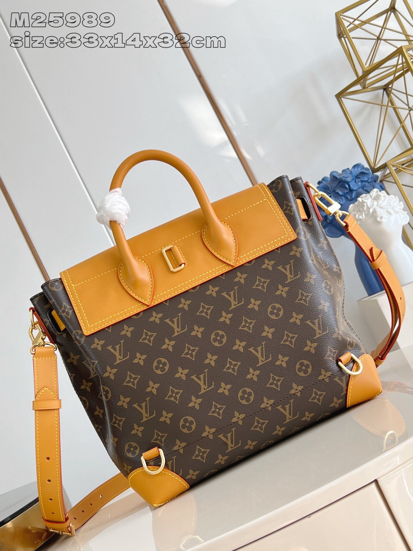 Louis Vuitton monogram handbag with structured top handles and tan leather crossbody strap