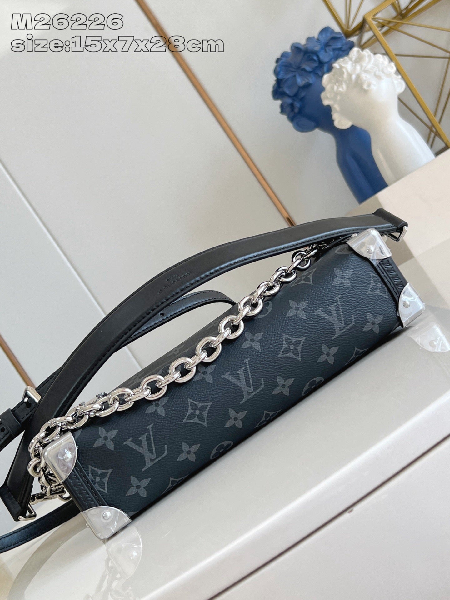 Crossbody bag side view with chain strap over dark monogram canvas