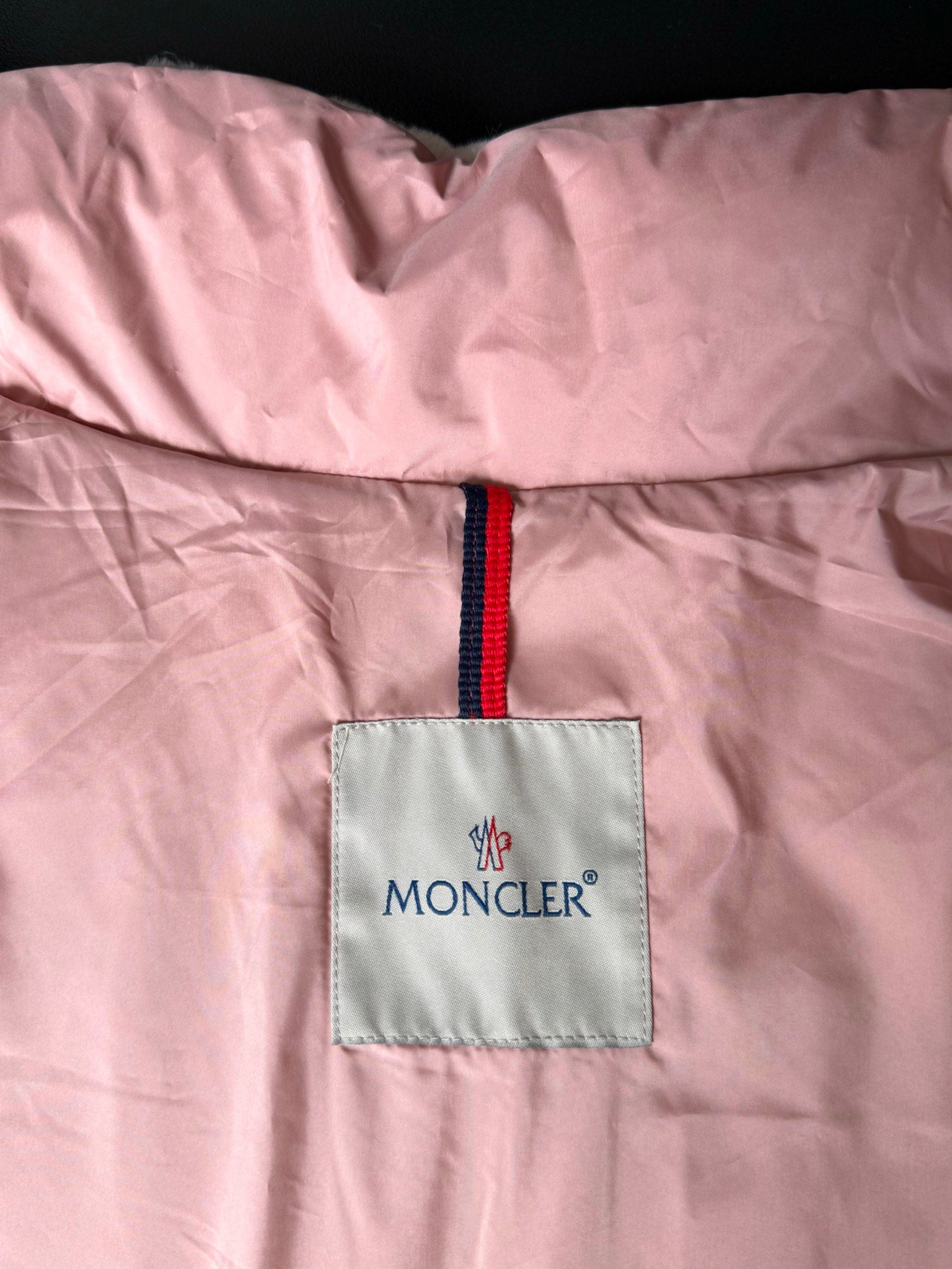 Moncler pink padded gilet with red logo zipper pull and fabric tag