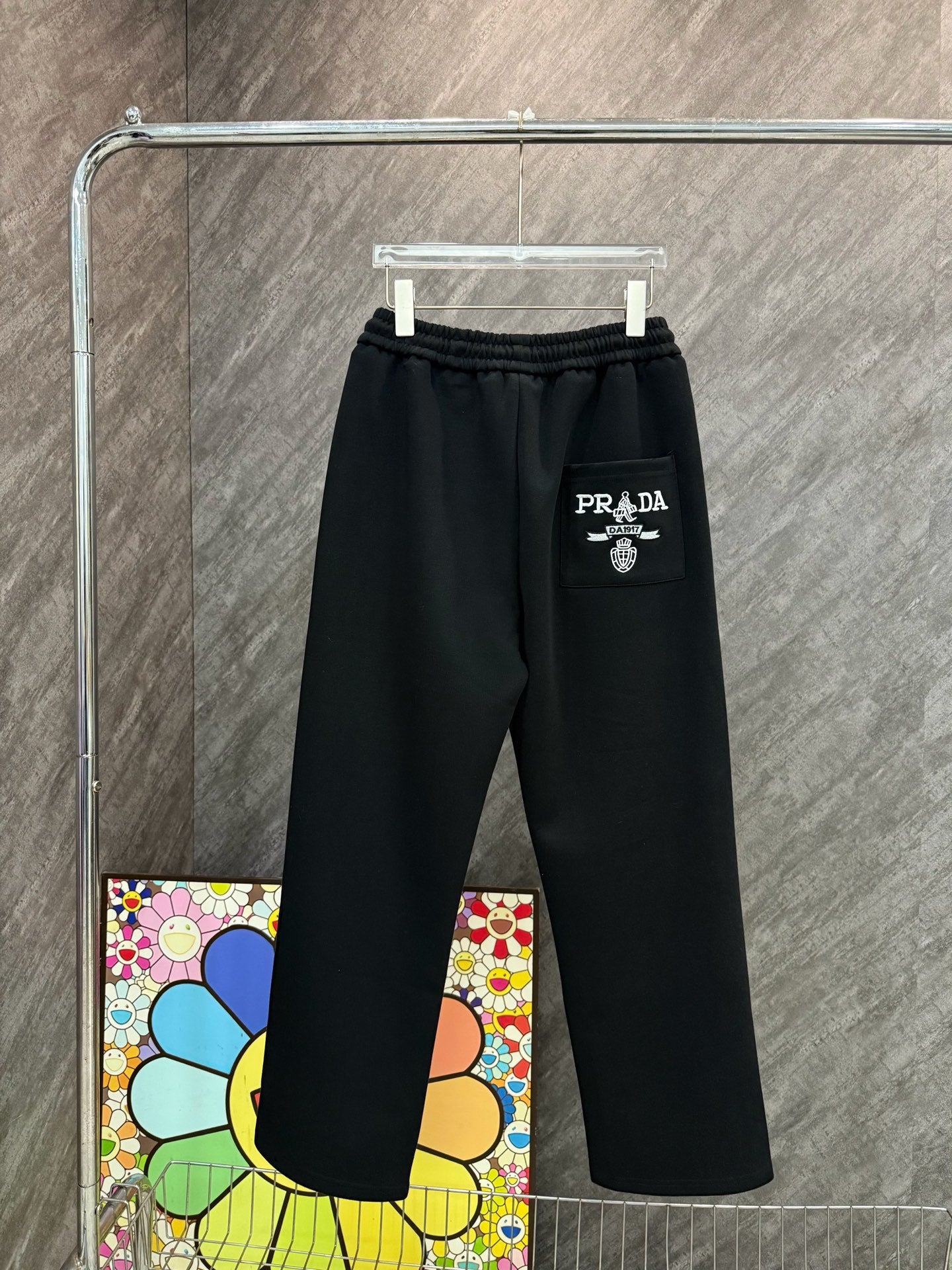 Black Prada pants with elastic waistband, straight leg, and PRADA patch logo.