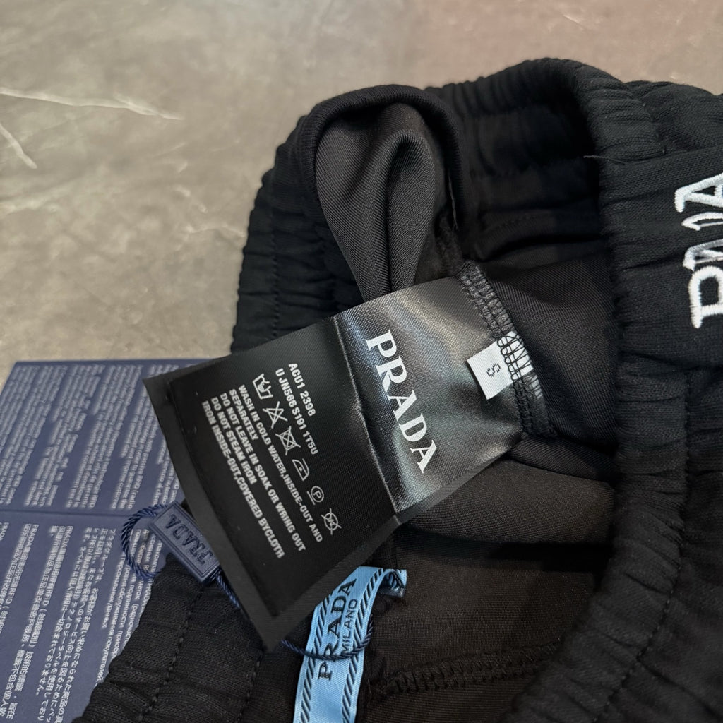 Black Prada pants with attached care tags and PRADA label on waistband.
