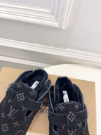 Pair of dark monogram slide sandals with adjustable buckle straps and plush lining.