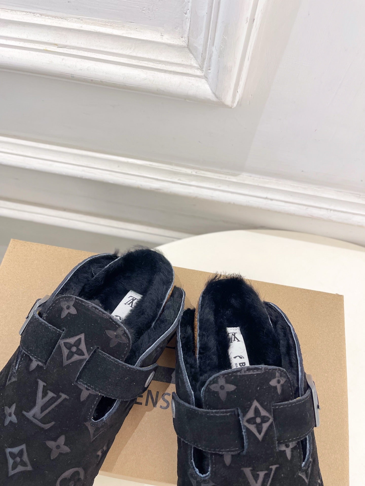 Pair of dark monogram slide sandals with adjustable buckle straps and plush lining.