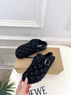 Monogram slide sandal with dark strap and metal buckle, plush lining inside.