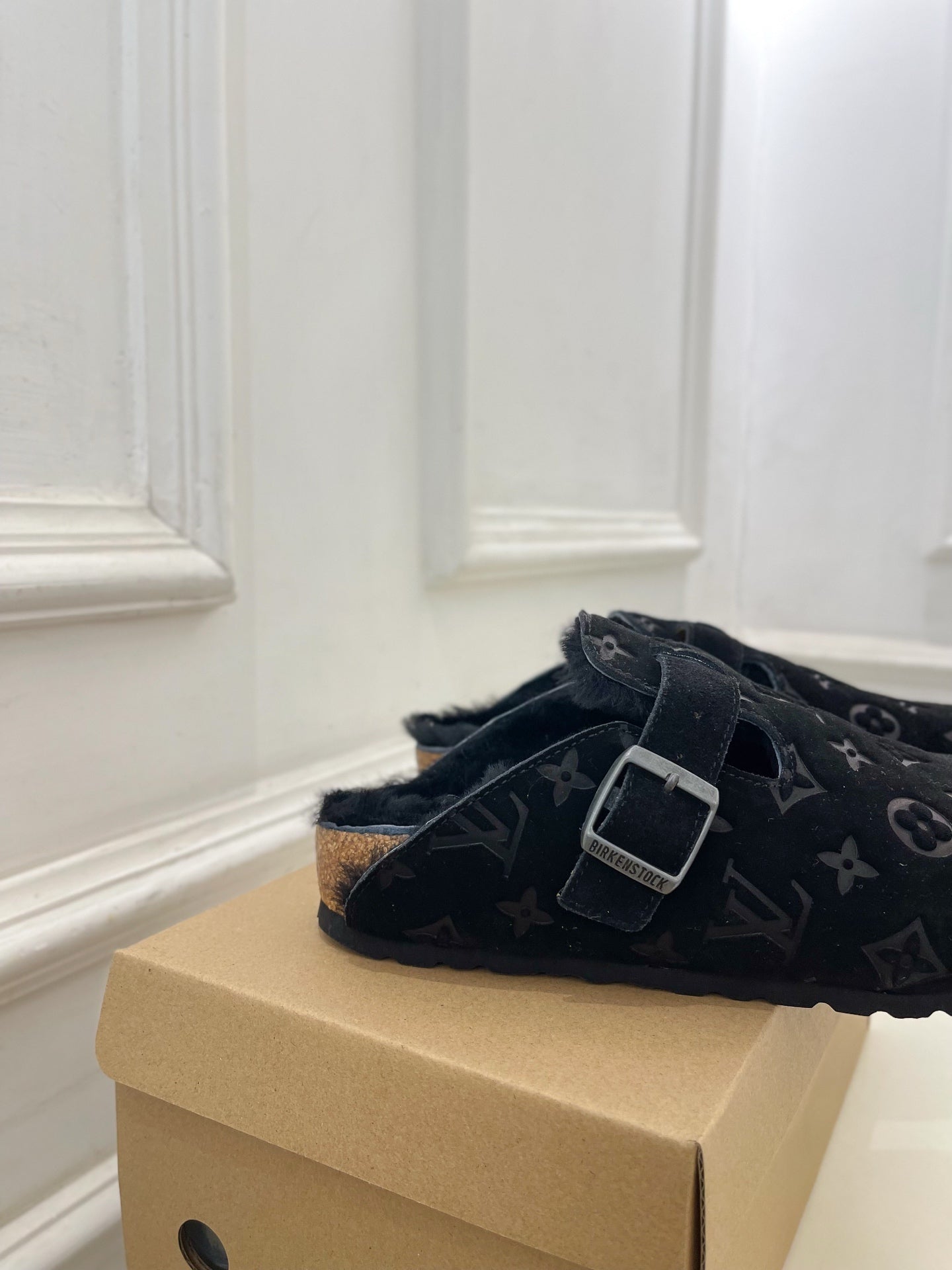 Dark monogram slide sandal with single adjustable buckle strap and textured outsole.
