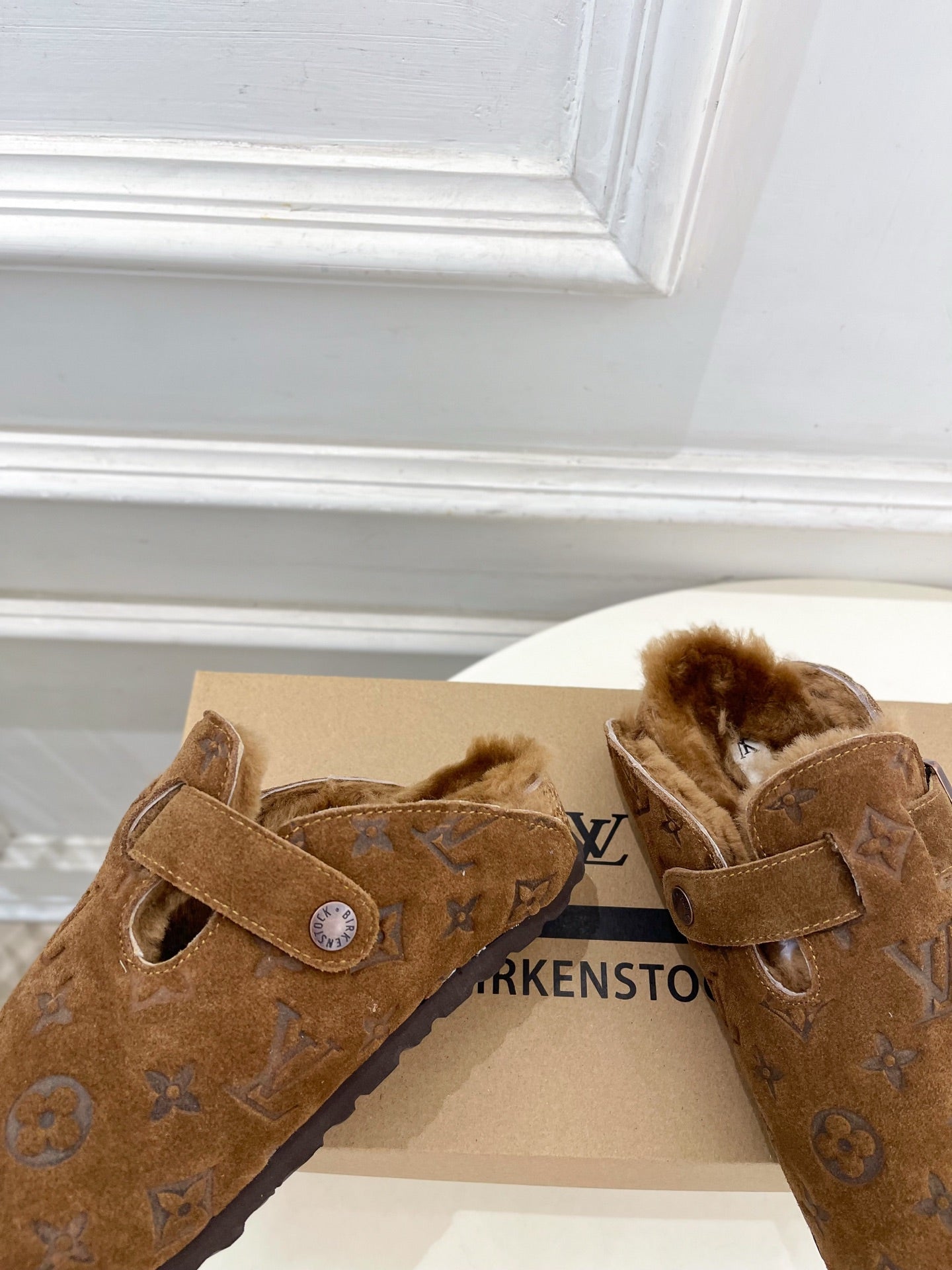 Brown suede clog sandals with buckle straps and shearling lining, close view