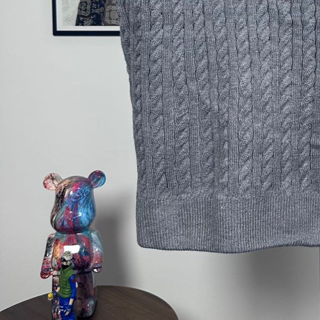 Long puffer jacket lower back hem in gray cable-knit with ribbed edge.