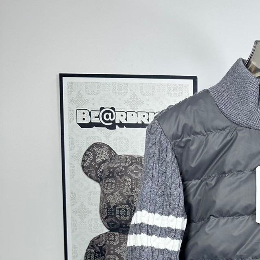 Stand collar and knit sleeves of a long puffer jacket with gray striped cuff.