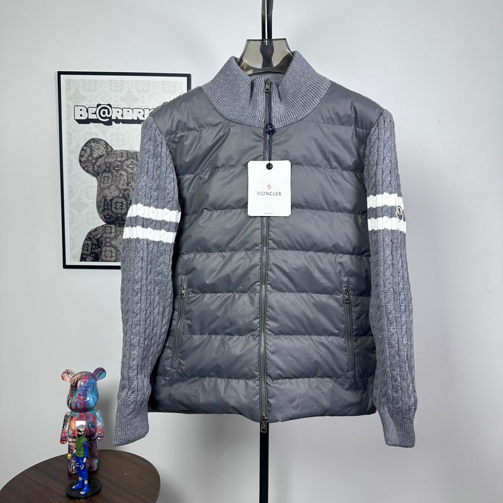 Long puffer jacket with stand collar, full zip, gray knit sleeves and striped cuffs.