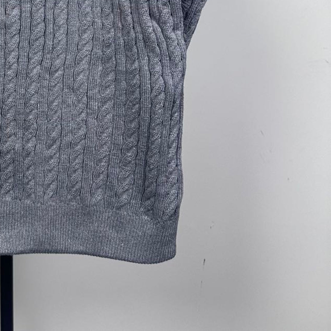 Long puffer jacket sleeve cuff in gray cable-knit with ribbed hem.