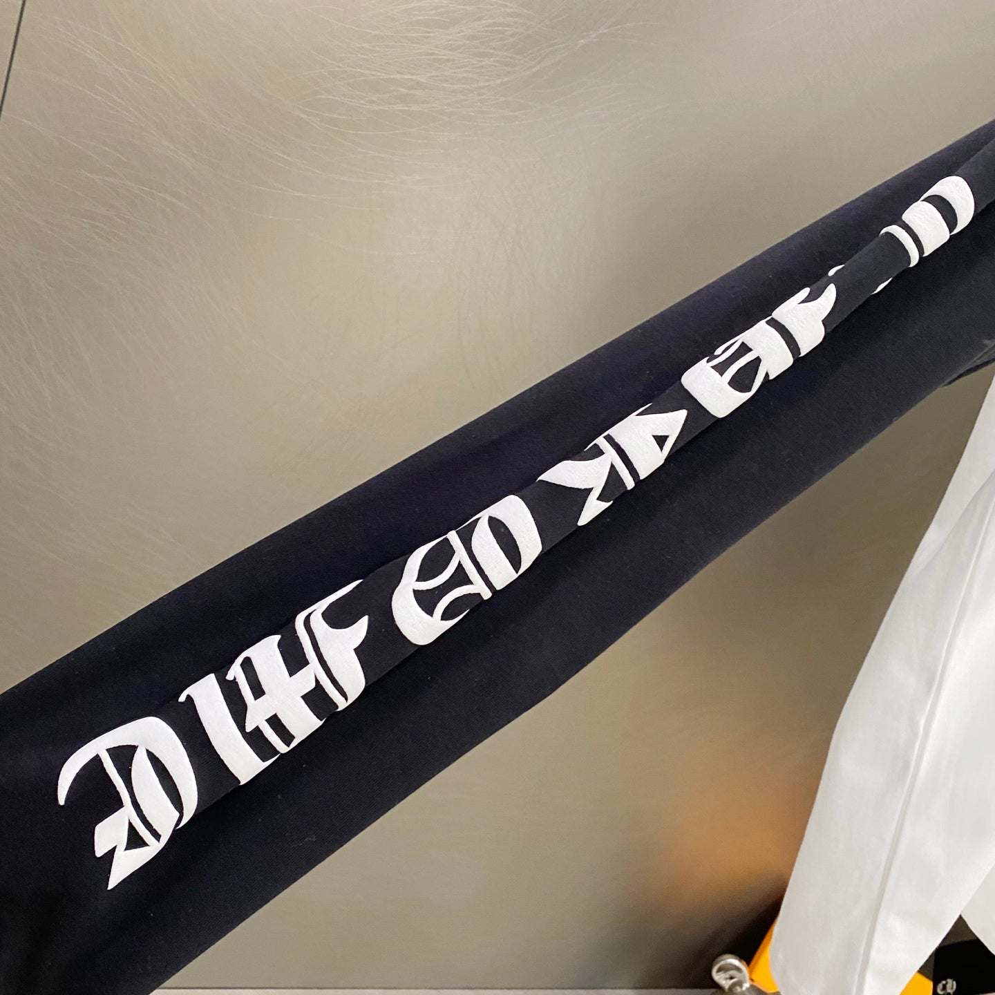 Long-sleeve shirt sleeve with white lettered graphic text on a dark sleeve panel.