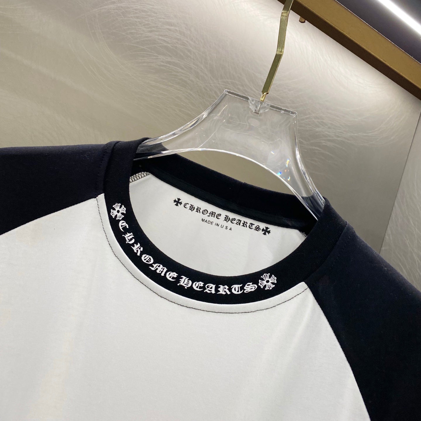 Long-sleeve shirt collar detail with black logo text band on white and black raglan.