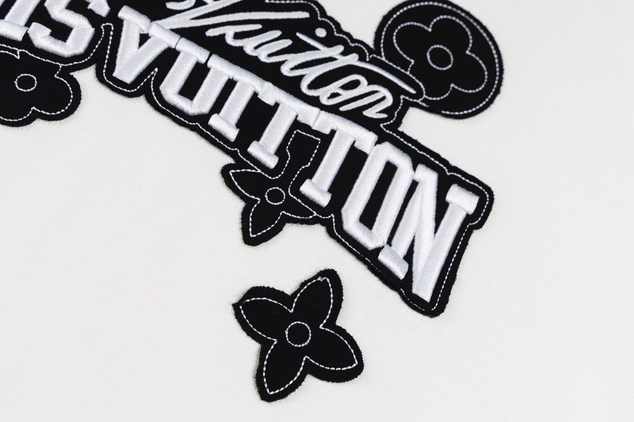 White long-sleeve sweatshirt logo close-up with outlined Louis Vuitton text