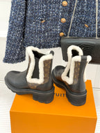 Black ankle boots with white shearling trim and brown monogram heel and side