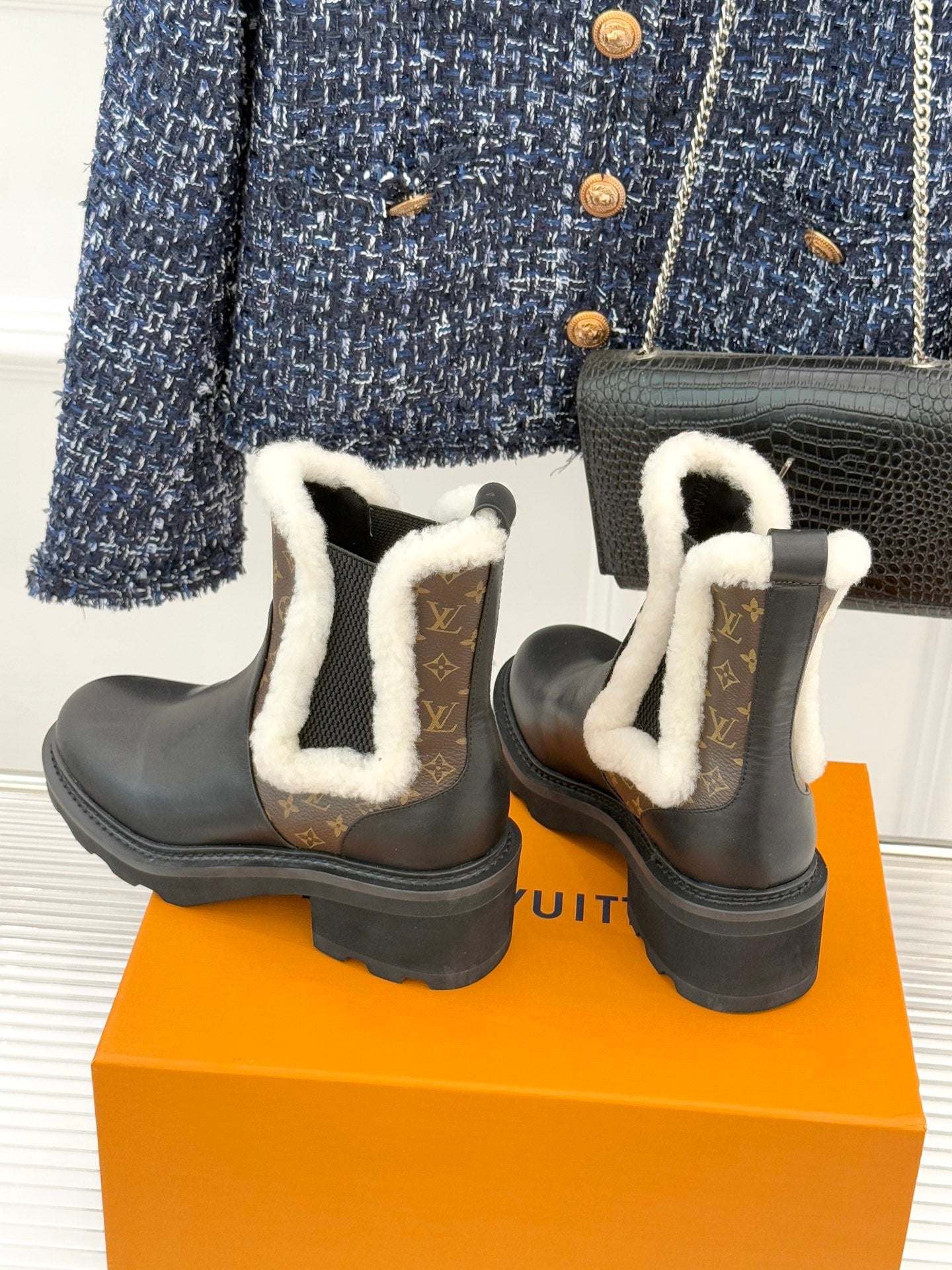 Black ankle boots with white shearling trim and brown monogram heel and side