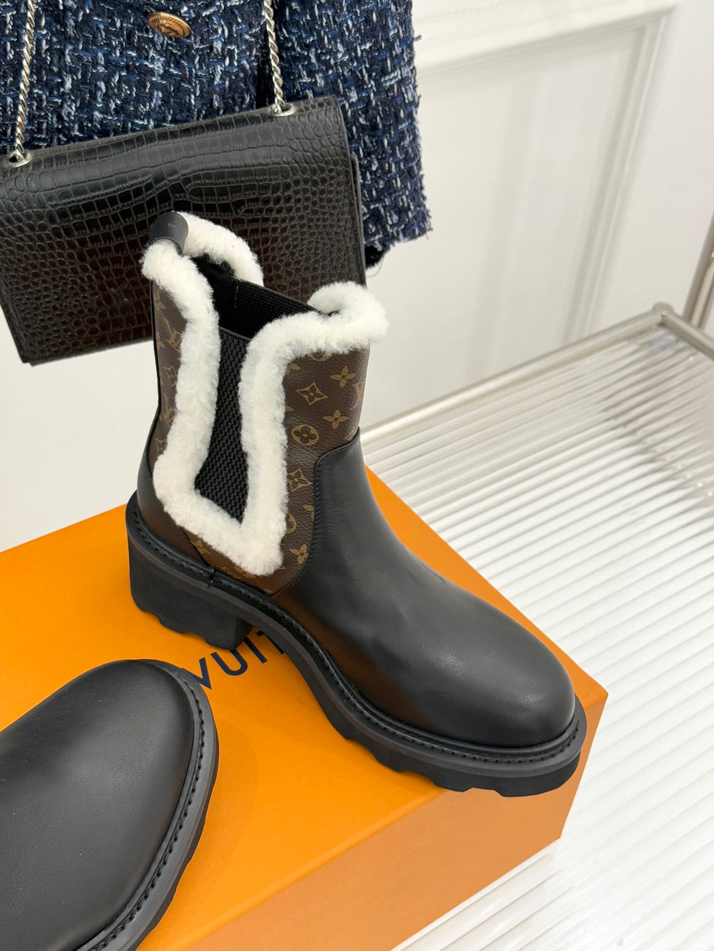 Black ankle boot with white shearling trim and brown monogram insets on side