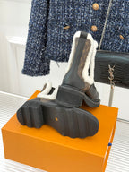 Ankle boot heel view with treaded rubber sole and brown monogram side detail