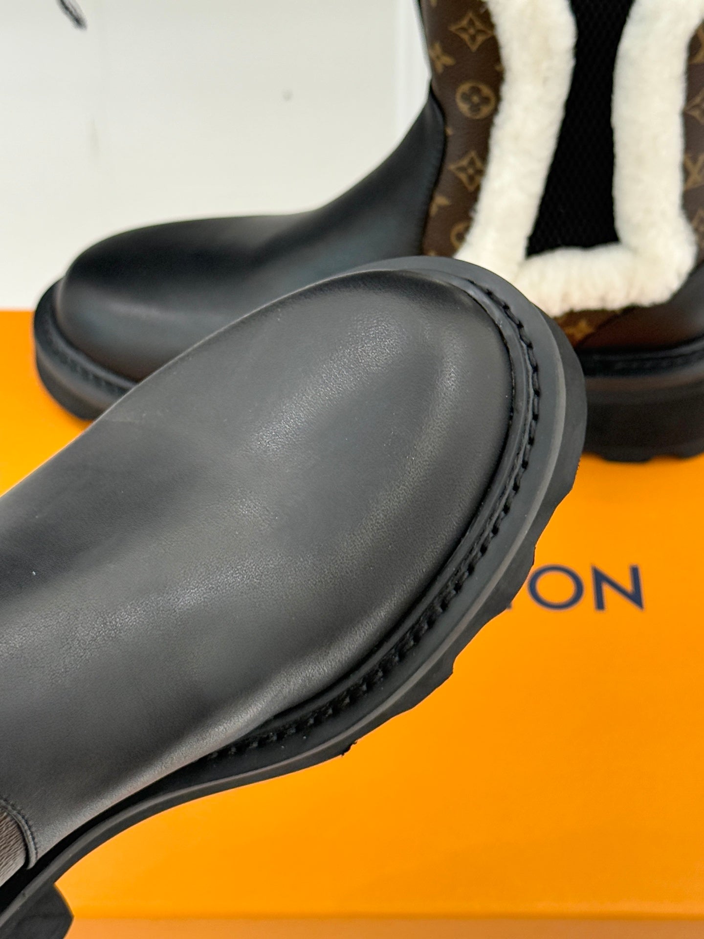Black ankle boot toe and side profile with textured stitching on rubber sole
