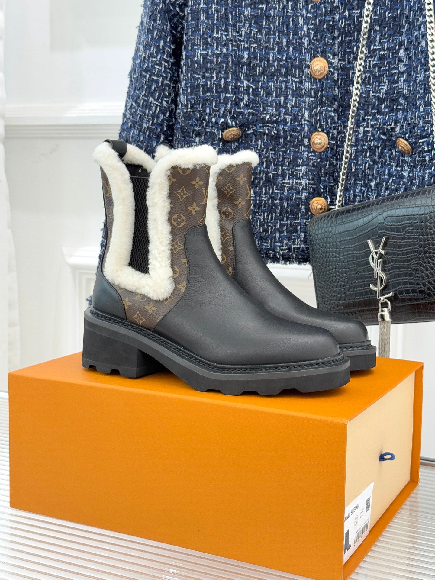 Black ankle boots with plush white shearling trim and dark rubber lug sole
