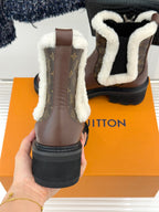 Brown Louis Vuitton ankle boots with white sherpa lining, chunky sole, and monogram sides